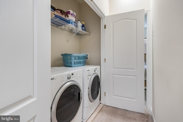 laundry room with independent washer and dryer, light colored carpet, and laundry area