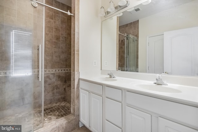 bathroom featuring double vanity, visible vents, a sink, and a stall shower