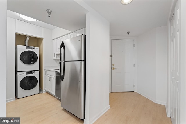 2400 Clarendon Blvd Unit 809, Arlington, VA 22201 - kitchen featuring freestanding refrigerator, stacked washer and clothes dryer, light wood-style flooring, white cabinets, and light countertops