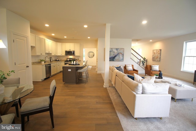 living area with baseboards, recessed lighting, wood finished floors, and stairs