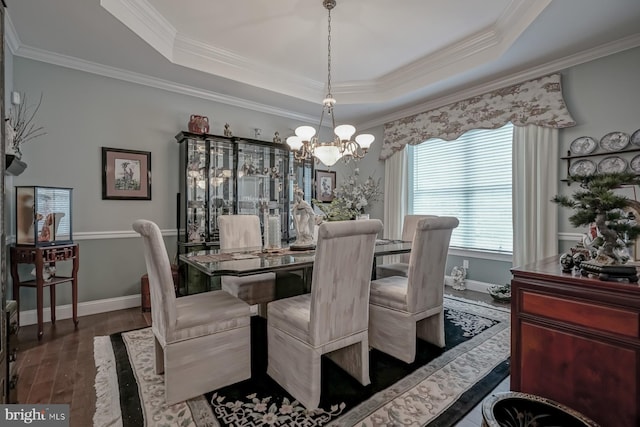 dining space featuring ornamental molding, baseboards, a notable chandelier, and a tray ceiling