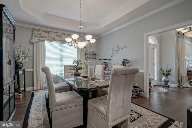 dining room with baseboards, a notable chandelier, wood finished floors, ornamental molding, and a raised ceiling