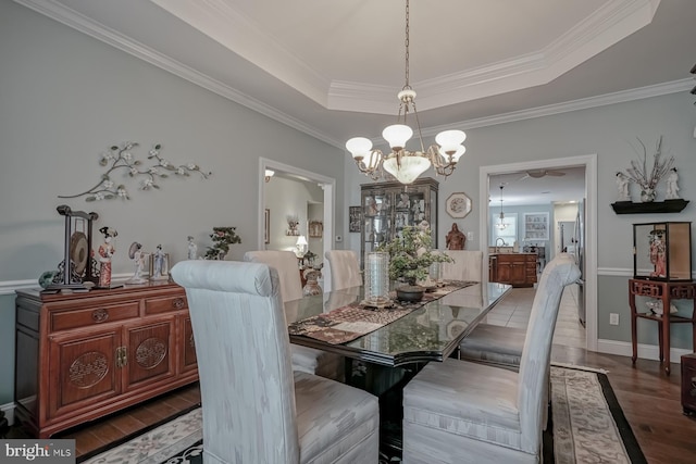 dining area featuring baseboards, a notable chandelier, wood finished floors, crown molding, and a raised ceiling