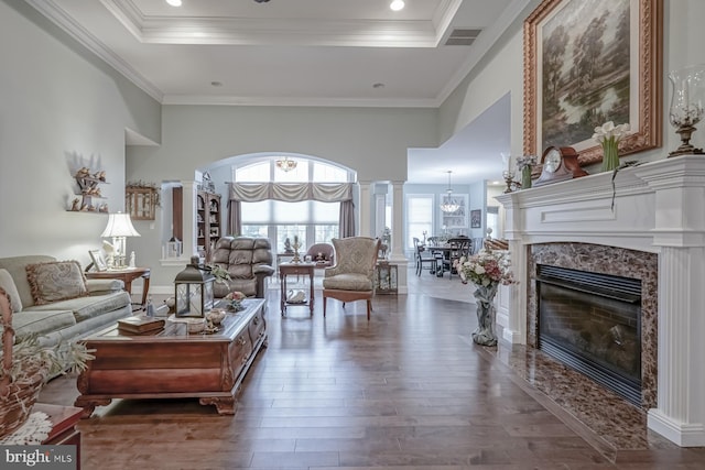 living room featuring crown molding, wood finished floors, a high end fireplace, a chandelier, and a raised ceiling