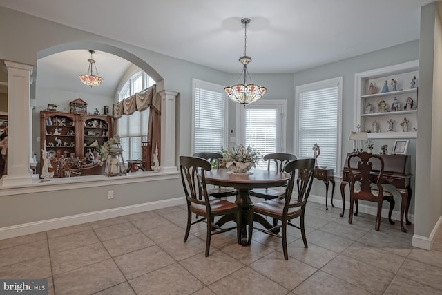 dining room featuring plenty of natural light, baseboards, arched walkways, and ornate columns