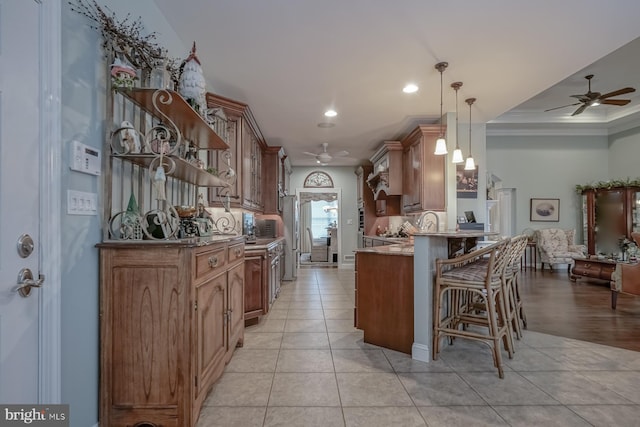 kitchen with a breakfast bar, light tile patterned floors, a peninsula, open floor plan, and ceiling fan
