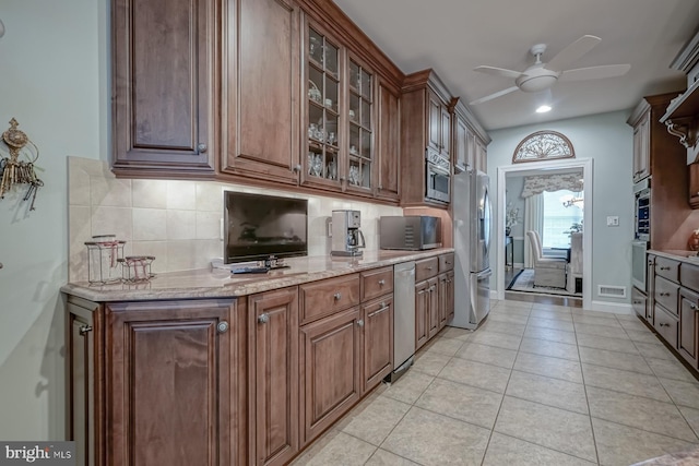 kitchen featuring light stone counters, visible vents, a ceiling fan, tasteful backsplash, and appliances with stainless steel finishes