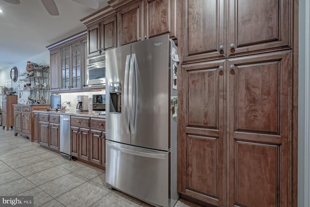 kitchen with glass insert cabinets, light tile patterned floors, ceiling fan, stainless steel fridge with ice dispenser, and dark brown cabinetry