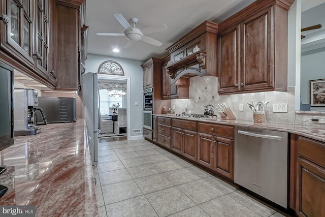 kitchen featuring light stone countertops, ceiling fan, decorative backsplash, and appliances with stainless steel finishes