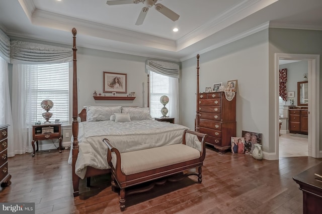 bedroom featuring wood-type flooring, baseboards, crown molding, and a tray ceiling