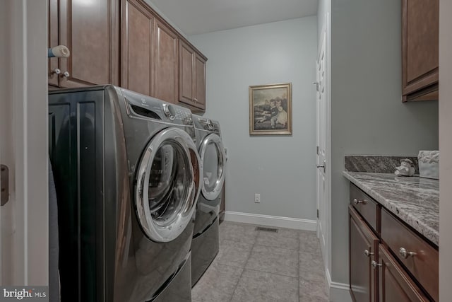 washroom featuring baseboards, visible vents, cabinet space, washer and dryer, and light tile patterned floors