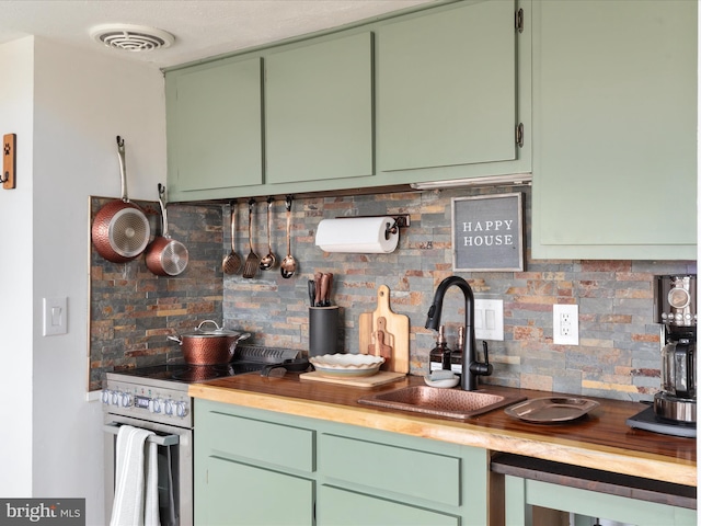 kitchen featuring stainless steel electric range, visible vents, decorative backsplash, green cabinetry, and a sink