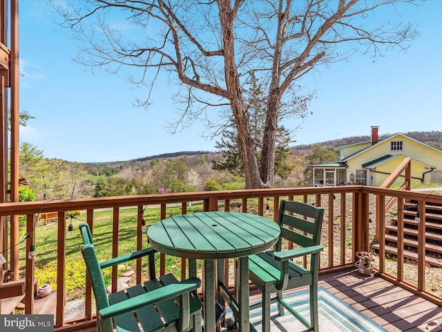wooden terrace featuring a view of trees and outdoor dining area
