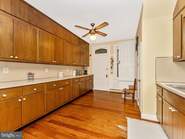 36 Fulton Ave, Walkersville, MD 21793 - kitchen with a baseboard radiator, ceiling fan, brown cabinets, light wood-style floors, and light countertops
