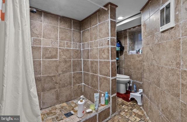 full bath featuring toilet and a tile shower