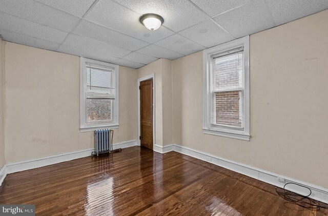 unfurnished room with radiator heating unit, a paneled ceiling, and hardwood / wood-style floors