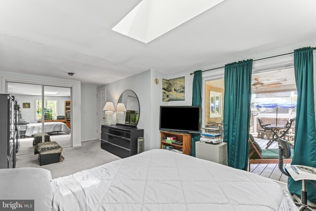 carpeted bedroom featuring a closet, baseboards, refrigerator, access to outside, and a skylight