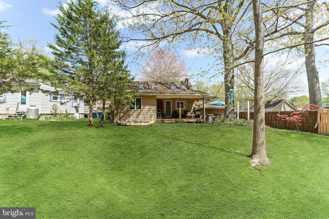 rear view of property with fence and a lawn