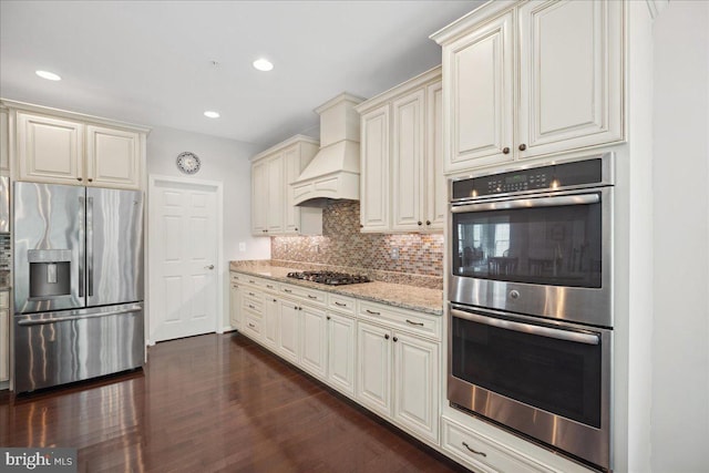 1230 Fairwood Dr, Huntingtown, MD 20639 - kitchen featuring backsplash, custom range hood, light stone counters, stainless steel appliances, and dark wood-type flooring