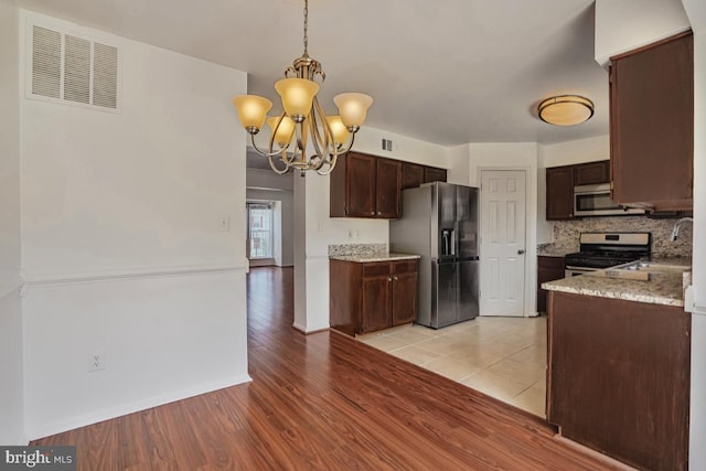 9403 Robin Lee Ct, Manassas Park, VA 20111 - kitchen featuring appliances with stainless steel finishes, a chandelier, light wood finished floors, decorative backsplash, and dark brown cabinetry