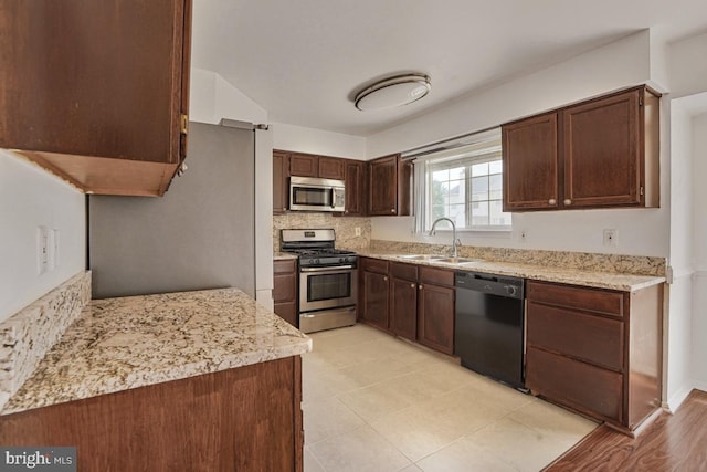 9403 Robin Lee Ct, Manassas Park, VA 20111 - kitchen featuring stainless steel appliances, a sink, dark brown cabinetry, decorative backsplash, and light stone counters