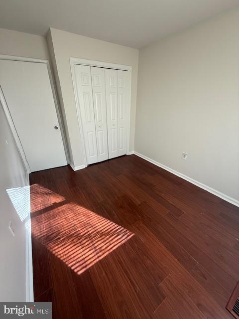 17 Rozina Ct, Owings Mills, MD 21117 - unfurnished bedroom with dark wood-style floors, a closet, and baseboards