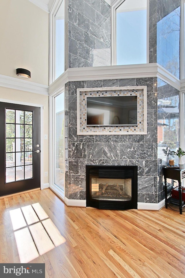 6704 Emporia Ct, Springfield, VA 22152 - entryway featuring ornamental molding, a tiled fireplace, baseboards, wood finished floors, and a towering ceiling