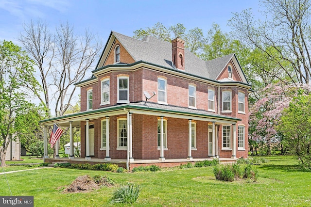 victorian home featuring a chimney, a porch, brick siding, and a front lawn