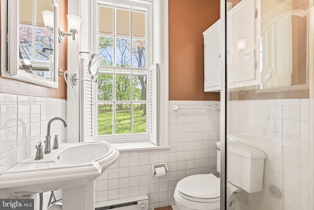 bathroom featuring a sink, tile walls, toilet, a wainscoted wall, and baseboard heating