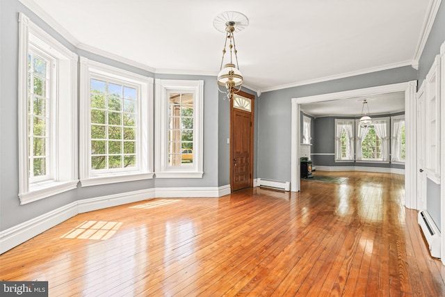 unfurnished dining area featuring baseboards, ornamental molding, baseboard heating, and hardwood / wood-style flooring