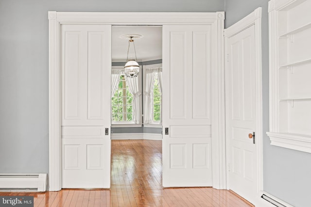 foyer with a chandelier, baseboards, baseboard heating, and hardwood / wood-style flooring