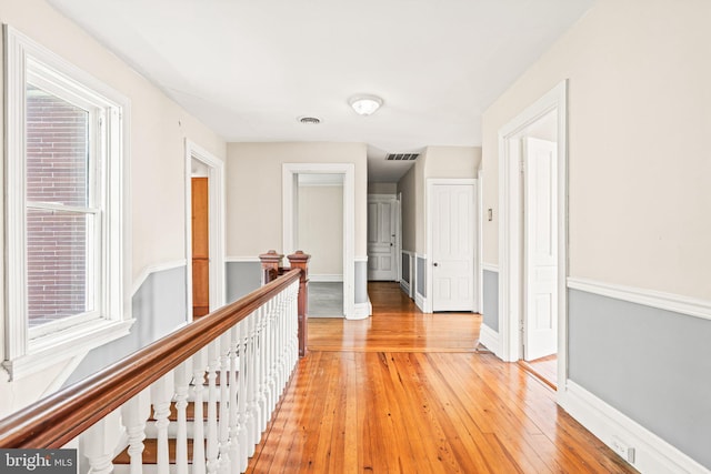 hall featuring baseboards, light wood finished floors, an upstairs landing, and visible vents