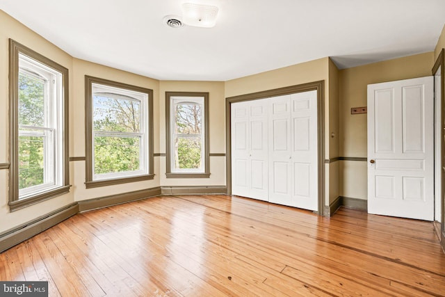 unfurnished bedroom featuring a closet, light wood-type flooring, visible vents, and baseboards