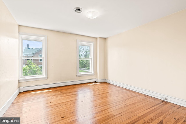 unfurnished room featuring baseboards, baseboard heating, and hardwood / wood-style floors