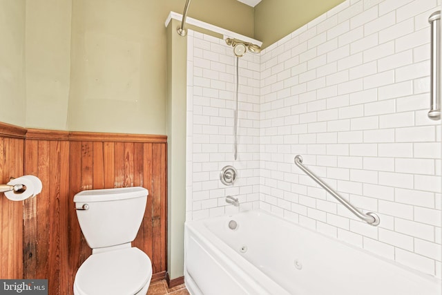 bathroom featuring toilet, wood walls, wainscoting, and shower / tub combination