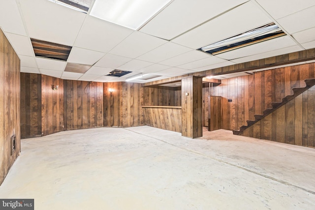 finished below grade area featuring stairway and wooden walls