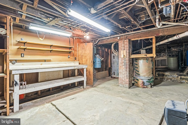 unfinished basement featuring a workshop area and water heater