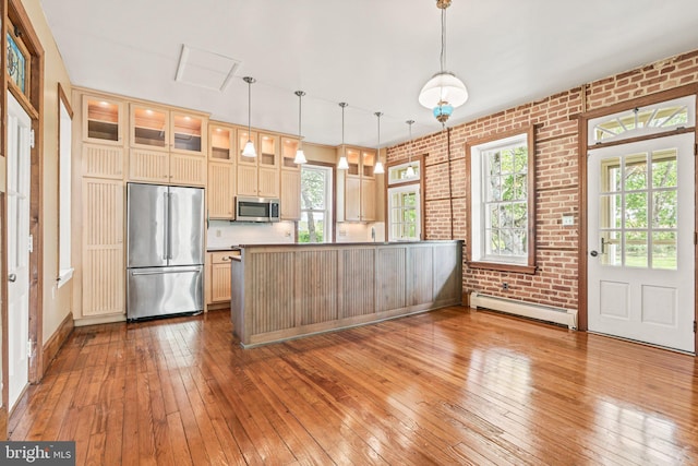 kitchen with stainless steel appliances, light wood-style flooring, a baseboard heating unit, and brick wall