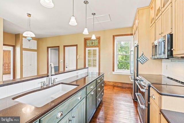 kitchen with decorative light fixtures, stainless steel appliances, dark wood-style flooring, and a sink