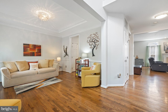 living area featuring wood finished floors, crown molding, and baseboards