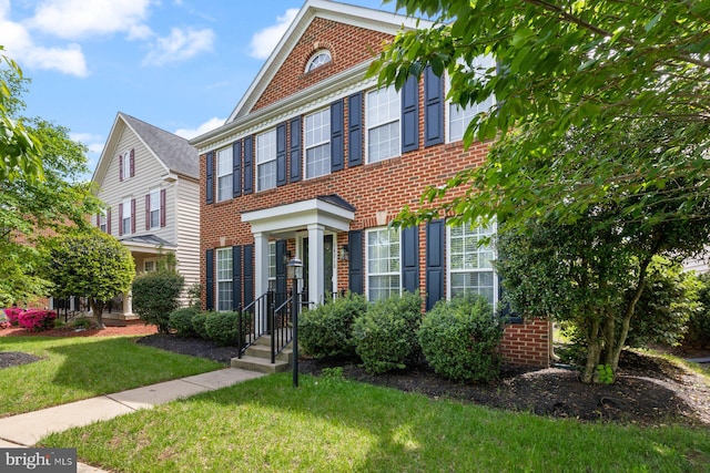 colonial-style house with brick siding and a front yard