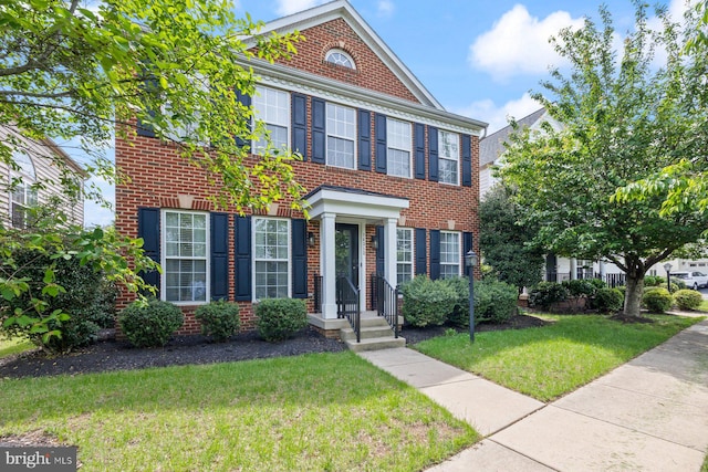 colonial-style house featuring brick siding and a front lawn