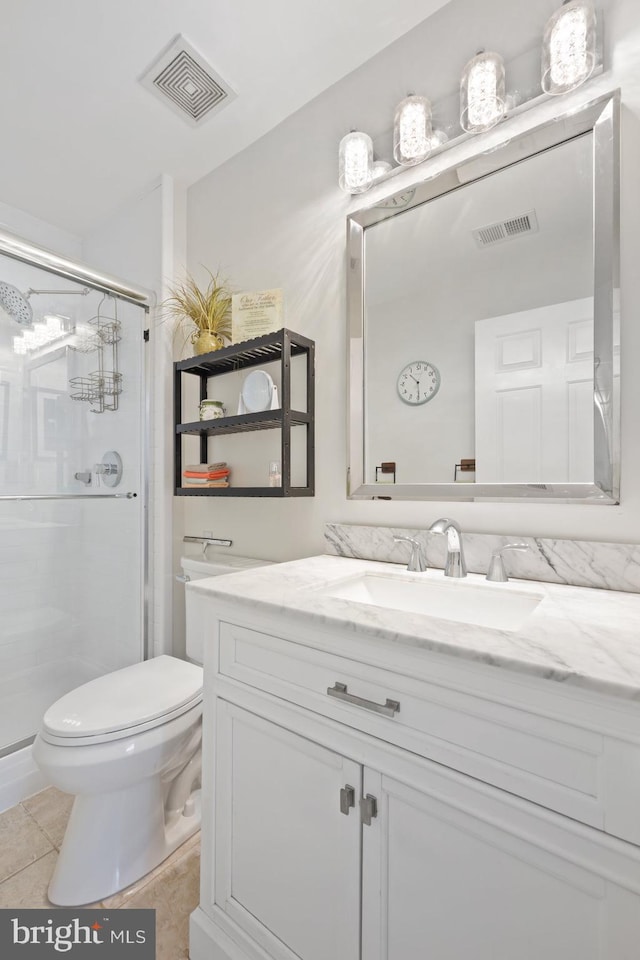 bathroom featuring toilet, vanity, a stall shower, and tile patterned floors
