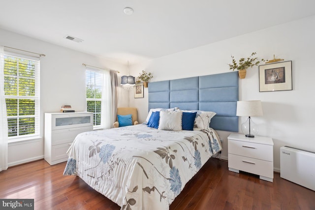 bedroom featuring wood finished floors, multiple windows, and baseboards