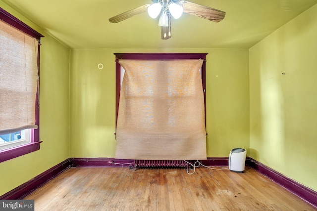 spare room with baseboards, a ceiling fan, and hardwood / wood-style floors