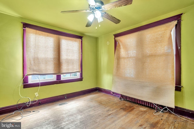 empty room featuring baseboards, wood finished floors, visible vents, and ceiling fan