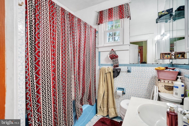 full bathroom with toilet, a shower with curtain, a sink, and tile walls