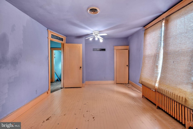 spare room featuring radiator, visible vents, a ceiling fan, and hardwood / wood-style flooring