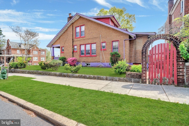 view of front of house featuring a front lawn, brick siding, and a chimney