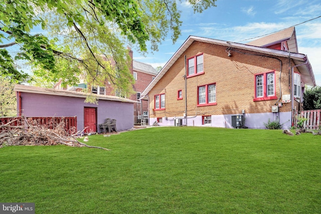 back of house featuring fence, a lawn, and brick siding